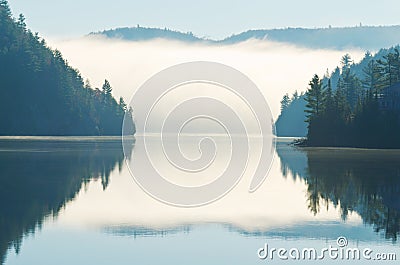 Reflection of Morning Fog Rising on Lake Stock Photo