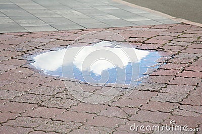 Reflection of sky in puddle on street tiles outdoors Stock Photo