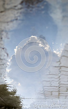 Reflection of white cloud and blue sky in puddle on paving slabs Stock Photo