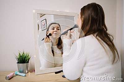 Reflection of a woman making-up with blush brush Stock Photo