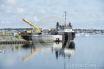 Reflections of crane and docked offshore supply vessel Editorial Stock Photo