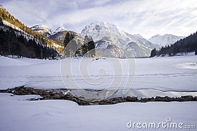 Frozen lake covered in snow with snowy mountain in the back Stock Photo