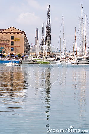 Reflections in the water of buildings and harbor cranes of Porto Antico in Genoa, Liguria, Italy, Europa. Editorial Stock Photo