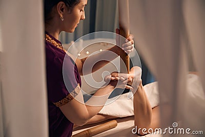 Reflexologist pressing with massage tool on acupoint on client sole Stock Photo