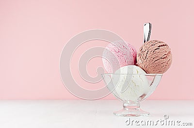 Refreshing classic white, pink, brown ice cream balls in glass bowl with silver spoon on white wooden table and soft light pink. Stock Photo