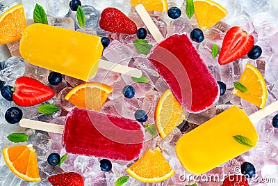 Refreshing fruit popsicle lollies on ice background with berries, peppermint Stock Photo