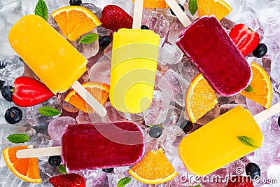 Refreshing fruit popsicle lollies on ice background with berries, peppermint. Stock Photo