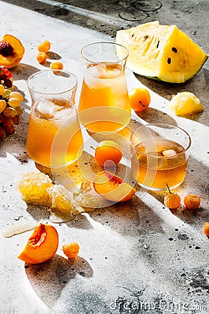 Refreshing peach ice tea or lemonade in glasses. Summer yellow fruit cocktail. Hard light harsh shadows. Stock Photo