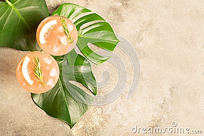 Refreshing summer cocktail grapefruit champagne juice in two glass goblets on the leaves of the Monstera plant Stock Photo