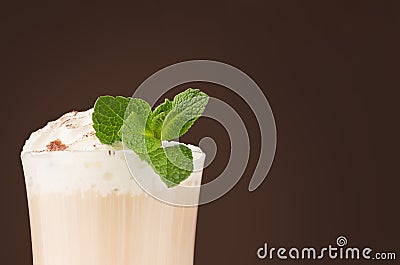 Refreshment coffee drink with fresh green mint, whipped cream, chocolate powder closeup, details, top sections of glass on brown. Stock Photo