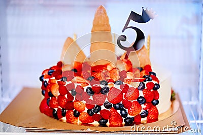 In refrigerator a birthday cake decorated with berries and a number five Stock Photo