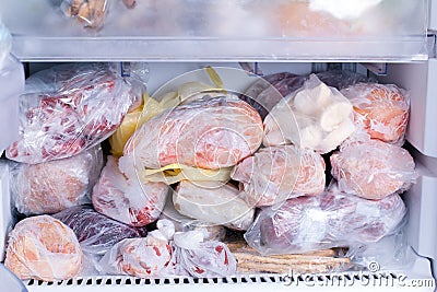 Refrigerator with frozen food. Open fridge freezer meat, milk, vegetables. Stock Photo