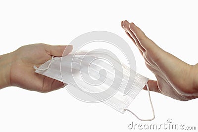 Refusal to wear a protective mask. Hand transmitting a medical mask, the second hand refuses with a gesture. Light background. Stock Photo