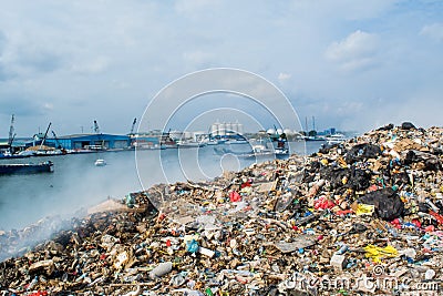 Refuse area near harbor view full of smoke, litter, plastic bottles,rubbish and trash at the Thilafushi local tropical island Stock Photo