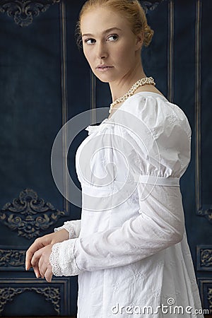 A Regency woman wearing a white cotton muslin dress and standing in a room Stock Photo