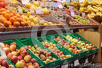 Regensburg, Germany - 2021 02 05: Various sorts of unpacked apples and other fruits in green plastic boxes and baskets on display Editorial Stock Photo