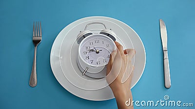 Daily regime, alarm clock on plate, adhere to diet time, proper nutrition Stock Photo