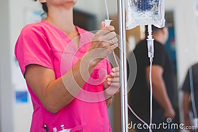 Registered nurse wearing hot pink scrubs hangs IV Stock Photo