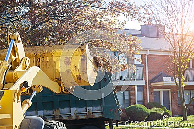 Regular seasonal work on city improvement team removes the fallen leaves with an excavator and a truck Stock Photo