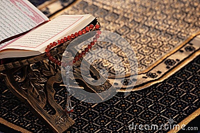 Rehal with open Quran and prayer beads on Muslim prayer mat. Stock Photo