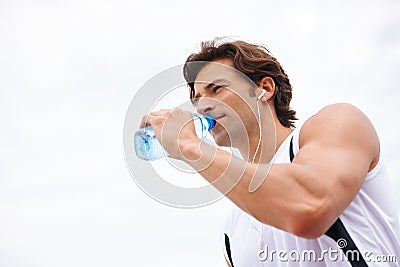 Rehydrating. a handsome young man taking a drink of water while working out. Stock Photo