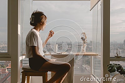 Relax asian woman eating at balcony window good warm vibes weekends lifestyle Stock Photo
