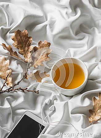 Relax cozy time - cup of green tea, music player headphones in bed. Top view Stock Photo