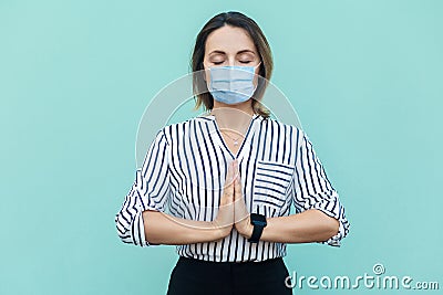 Relax and meditation. Portrait of calm middle aged woman with surgical medical mask standing and doing yoga alone Stock Photo