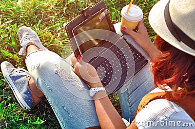 Relaxation with a cup of coffee and tablet.Girl with laptop an coffee. Beautiful young woman with notebook sitting on the grass. Stock Photo