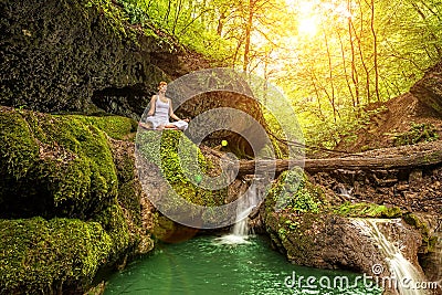 Relaxation in forest at the Waterfall. Ardha Padmasana pose Stock Photo