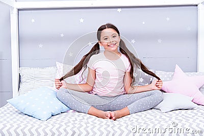 Relaxation and meditation. Girl child sit on bed in her bedroom. Kid prepare to go to bed. Pleasant time for evening Stock Photo