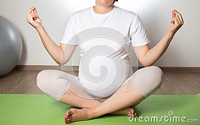 Relaxation and meditation for a pregnant girl on a fitball ball on a white background. Women Health Stock Photo