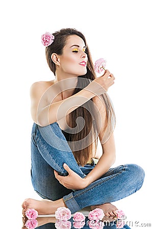 Relaxation, meditation. Young beautiful woman sitting on the floor in jeans. The girl holds a rose in hands. Stock Photo