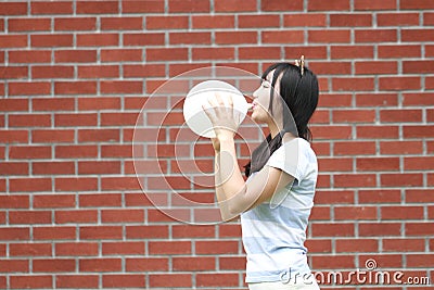 Relaxed Asian Chinese girl blow up a balloon and enjoy free time on the lawn Stock Photo