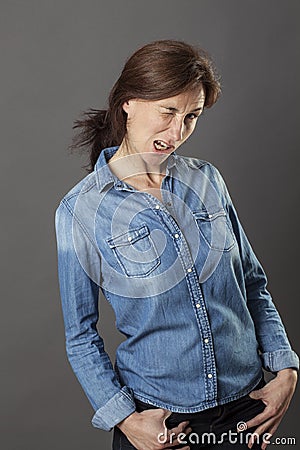 Relaxed beautiful middle aged woman winking with hands in pockets Stock Photo