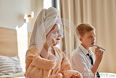 Relaxed children begin the day together, brush teeth Stock Photo