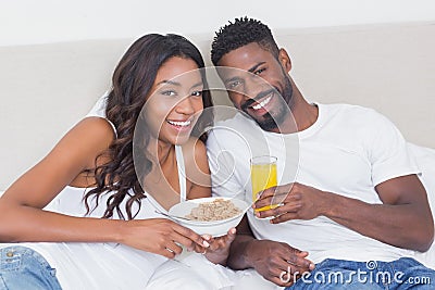 Relaxed couple in bed together eating cereal Stock Photo
