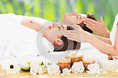 Relaxed Couple Receiving Head Massage At Spa Stock Photo
