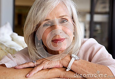 Relaxed older woman smiling and sitting on sofa Stock Photo