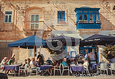 Relaxed people sitting at local restaurant, eating sea food at sunny historical town street Editorial Stock Photo