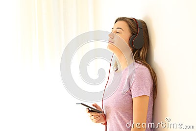 Relaxed teen listening to music on leaning a wall Stock Photo