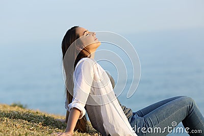 Relaxed woman breathing fresh air sitting on the grass Stock Photo