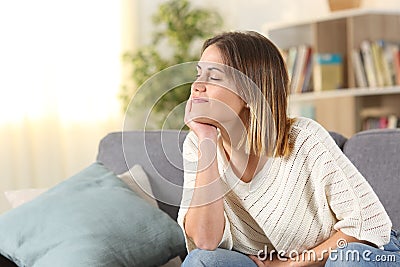 Relaxed woman meditating sitting on a couch at home Stock Photo