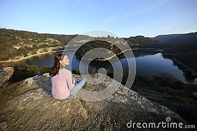 Relaxed woman sitting contemplating nature in a river Stock Photo
