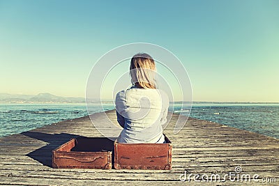 Relaxed woman sitting in her big suitcase after a long journey Stock Photo