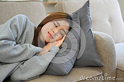 Relaxed young Asian female taking an afternoon nap on the sofa, fall asleep on couch Stock Photo