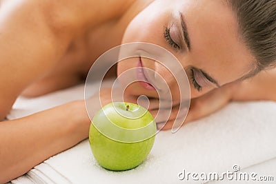 Relaxed young woman with apple laying on massage table Stock Photo