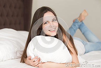 Relaxed young woman lying in bed on stomach Stock Photo