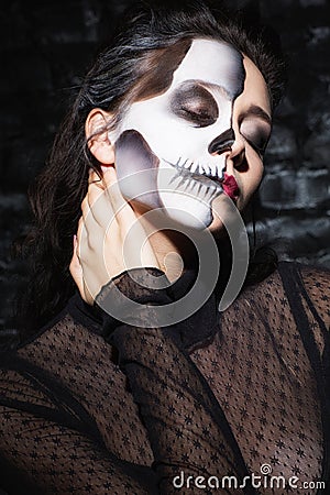 Relaxed young woman with skull make up touching neck. Stock Photo