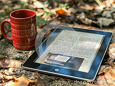 Relaxing autumn scene ereader displaying text lies on fallen leaves beside a rustic red mug. Perfect for blog posts, articles Stock Photo